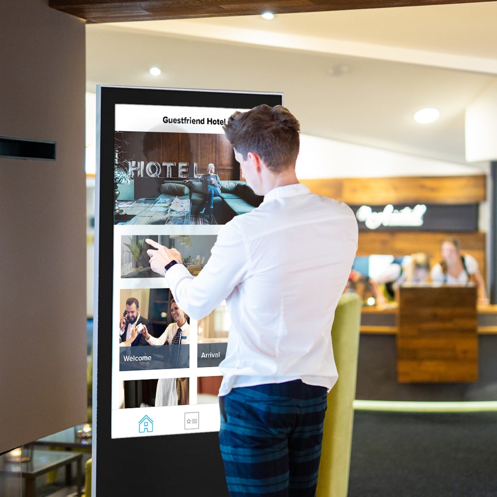 A man using the touchscreen kiosk as a digital information point next to the reception desk.